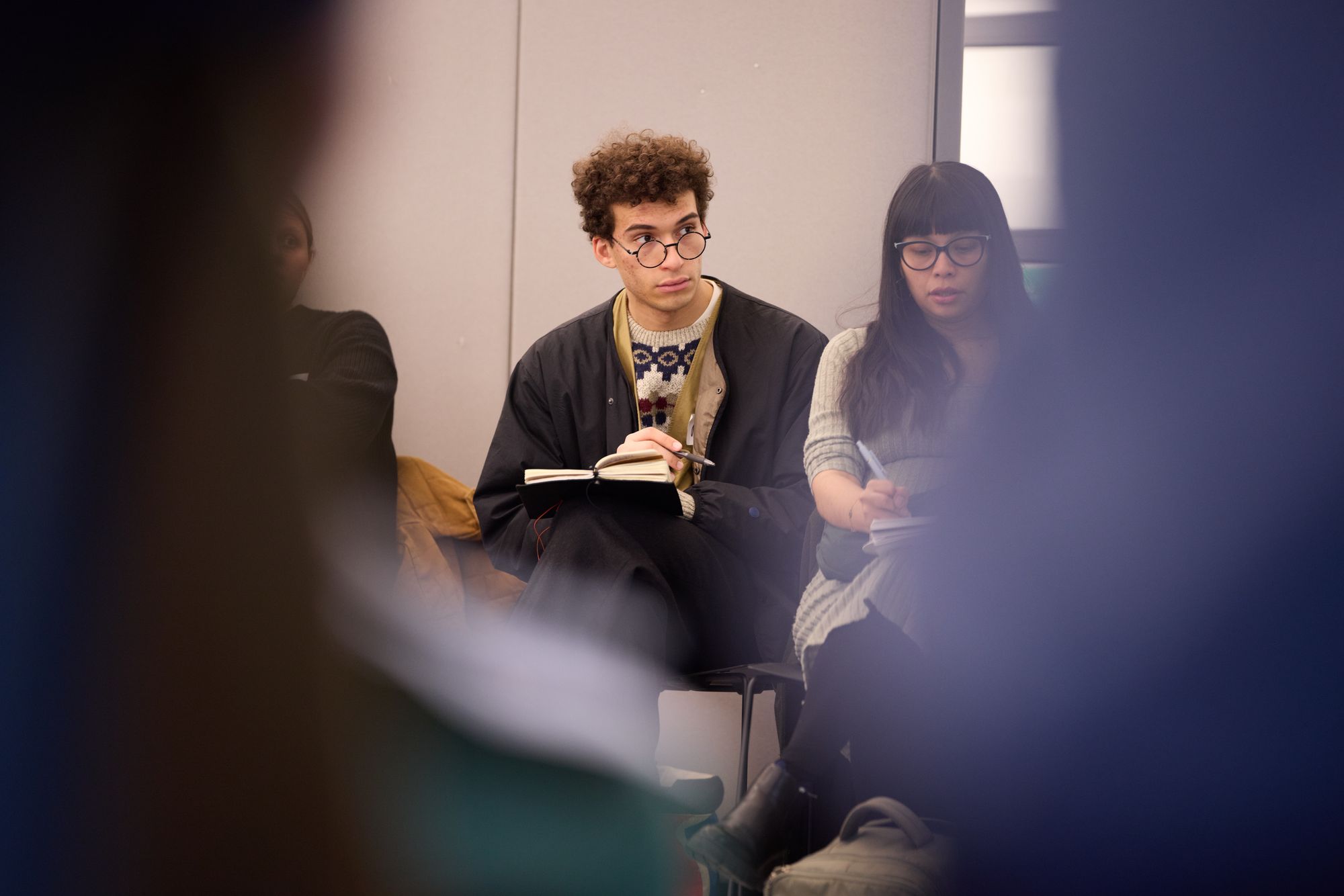 A participant listens thoughtfully while seated in a large circle of attendees.